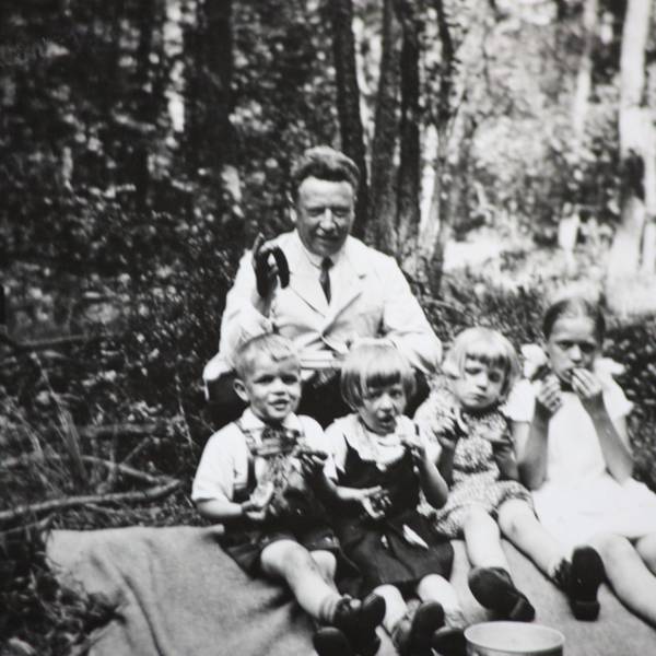 Edmund Schiefeling sitzt gemeinsam mit vier Kindern auf einer Decke beim Picknick im Wald.