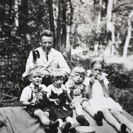 Edmund Schiefeling sitzt gemeinsam mit vier Kindern auf einer Decke beim Picknick im Wald.