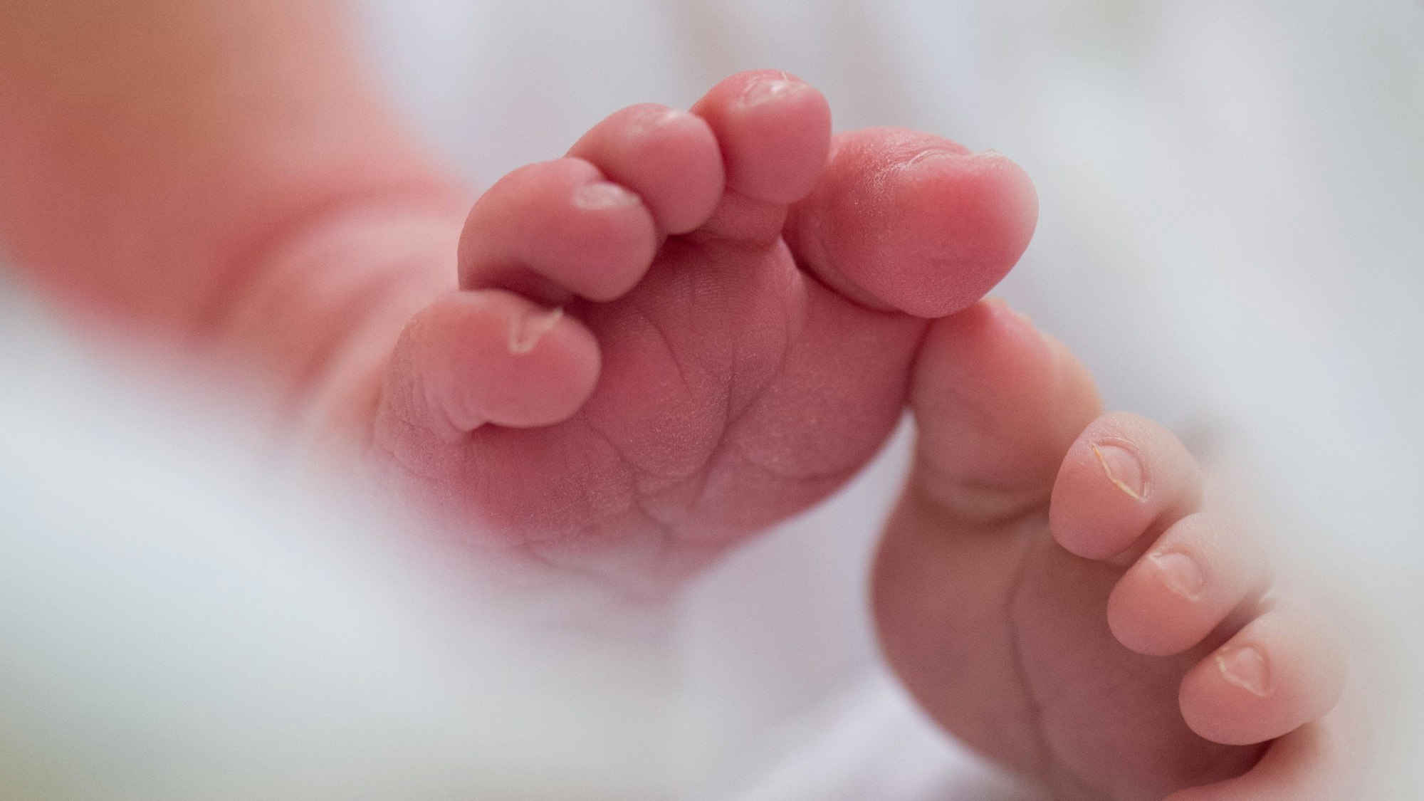 Ein Säugling liegt am in einem Bett auf der Wochenstation in einem Universitätsklinikum.
