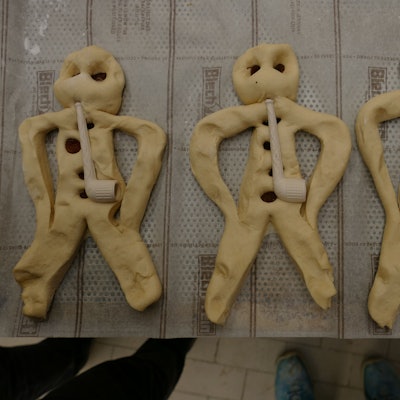 Aus Teig geformte Weckmänner liegen auf einem Backblech.