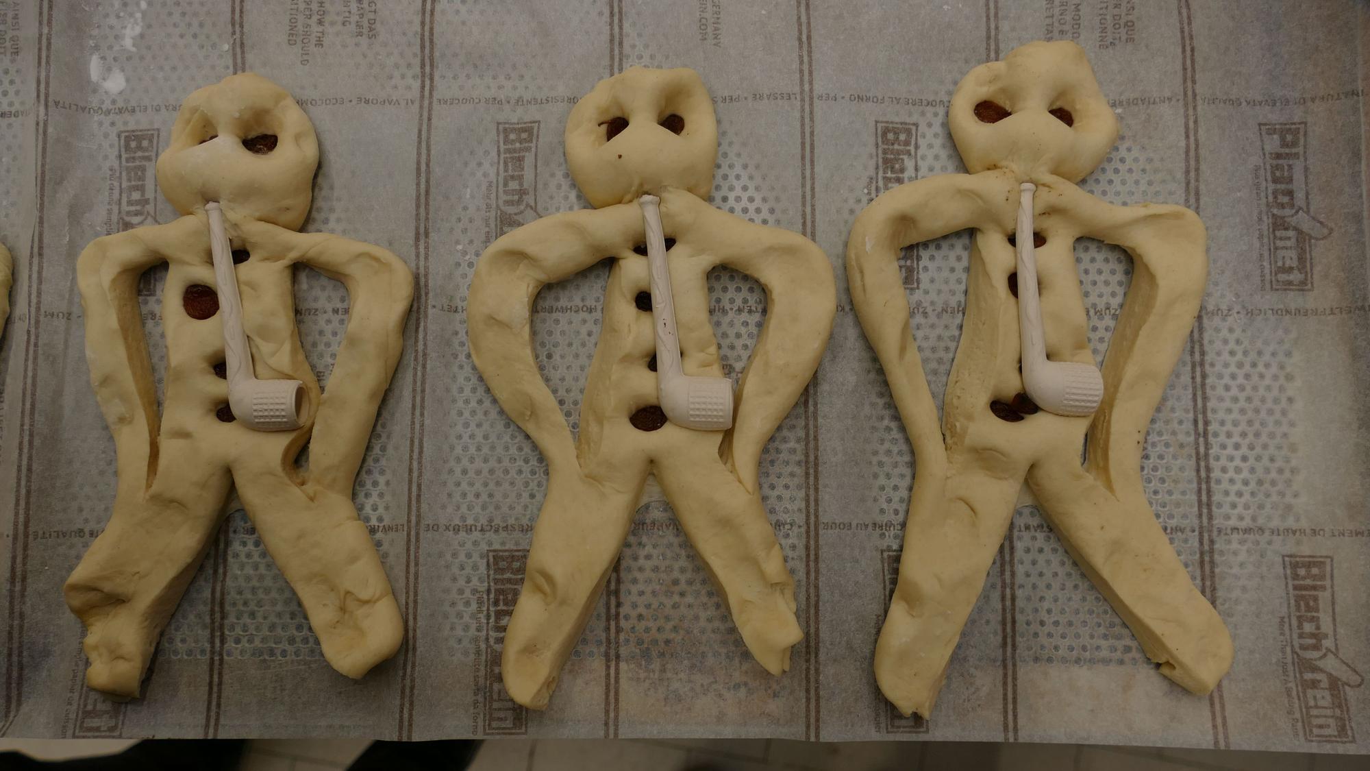 Aus Teig geformte Weckmänner liegen auf einem Backblech.