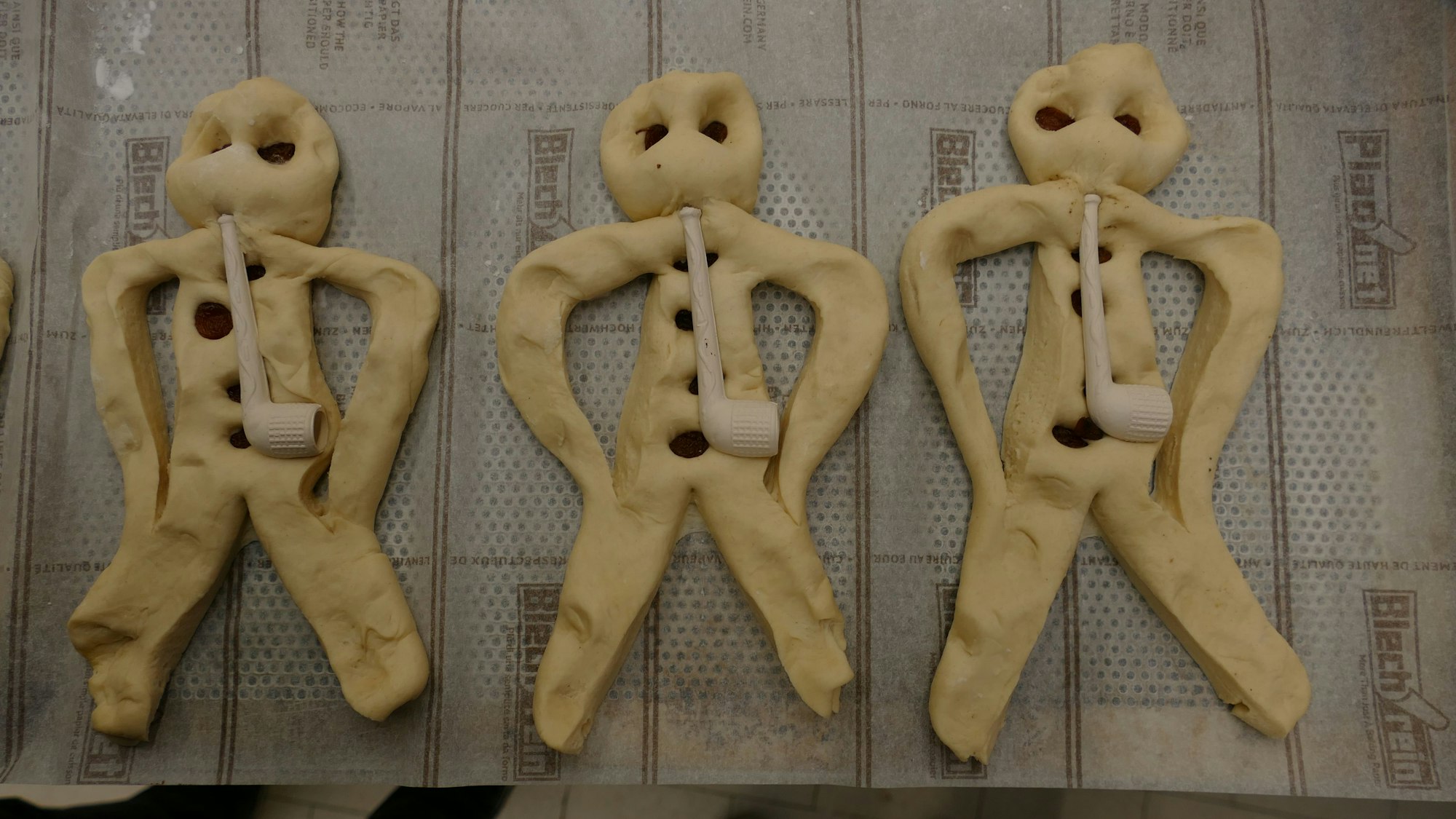 Aus Teig geformte Weckmänner liegen auf einem Backblech.