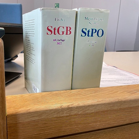 Das Bild zeigt Gesetzbücher auf dem Richtertisch eines Gerichts.