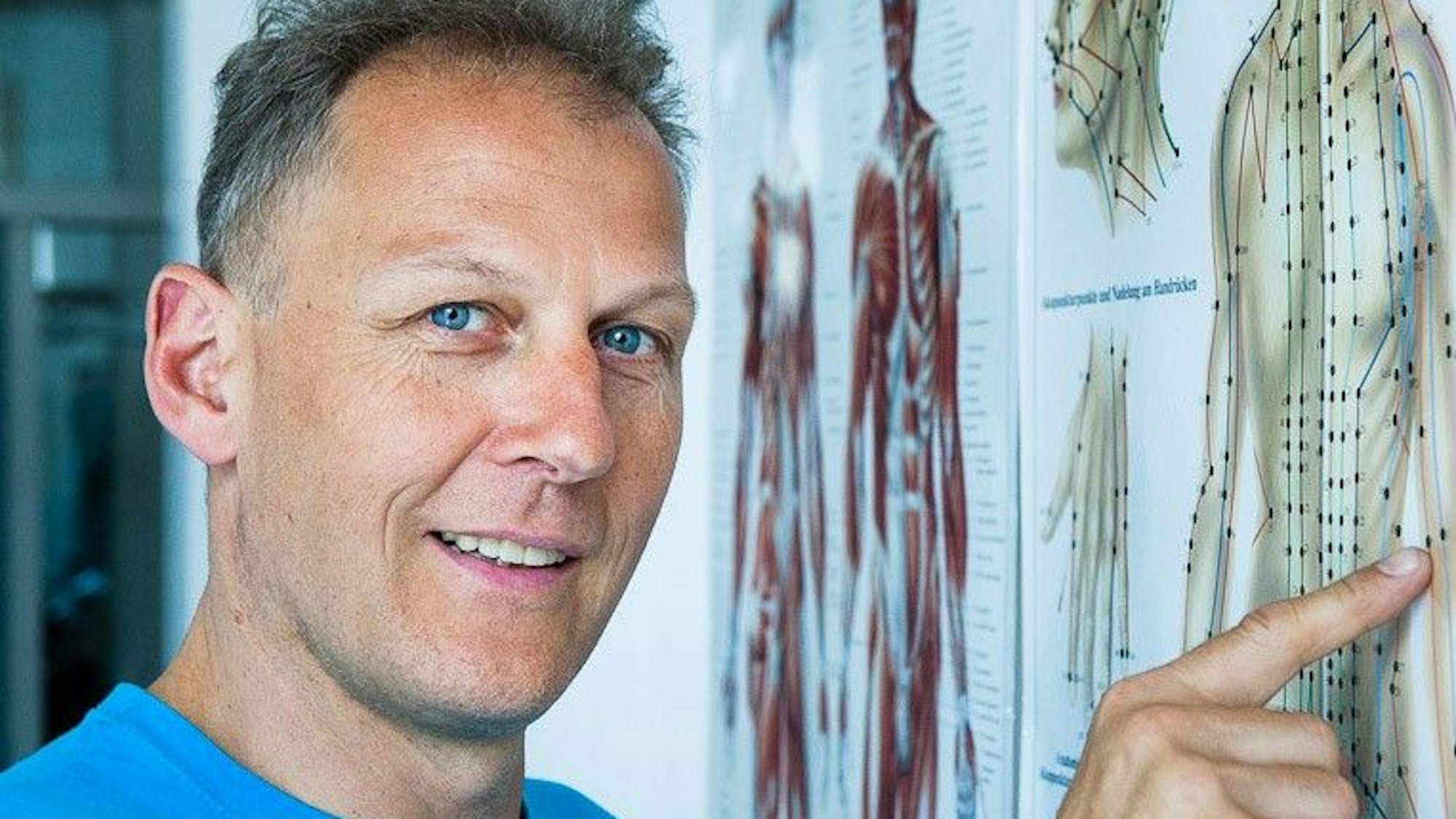 Heilpraktiker Markus Rachl zeigt auf eine Karte mit einem gezeichneten Körper.
