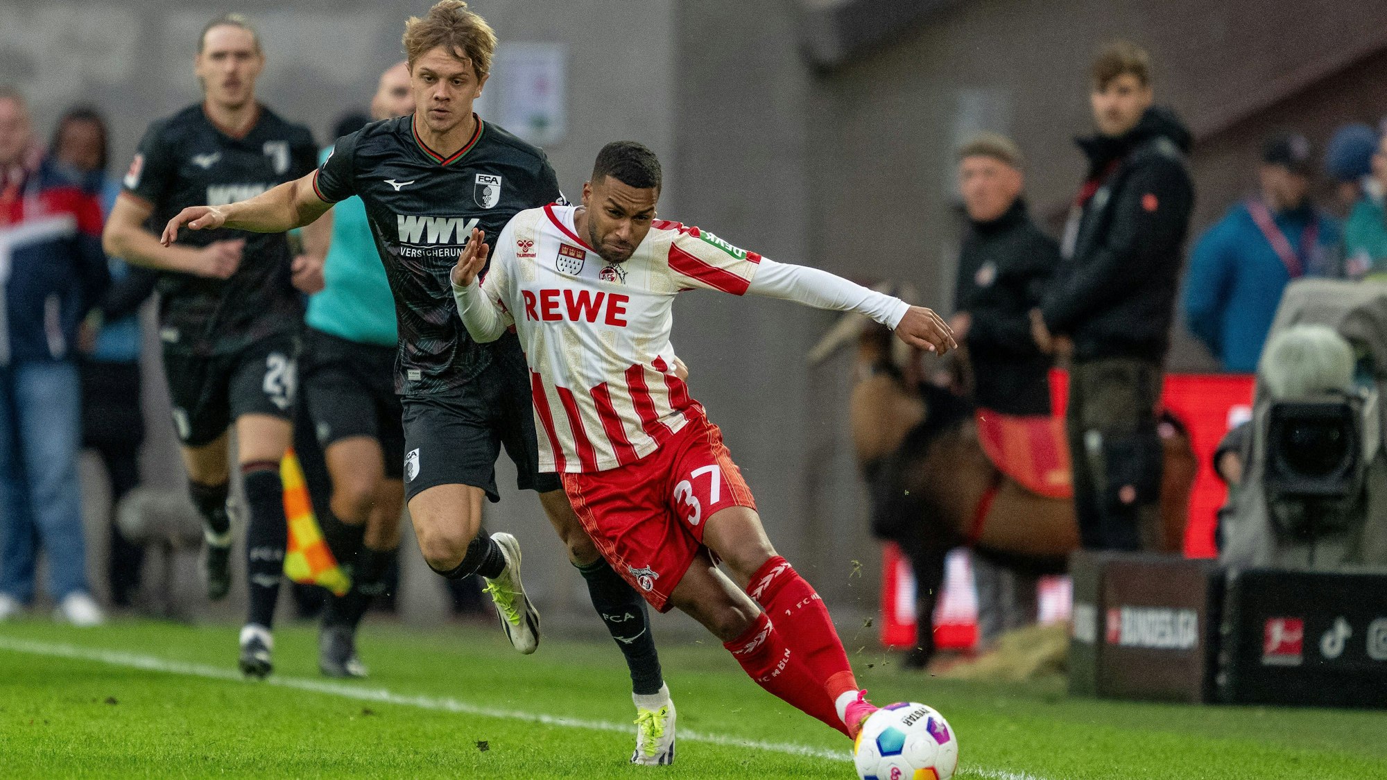 Kölns Linton Maina (r) im Zweikampf mit Augsburgs Robert Gumny.