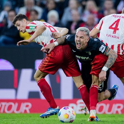 Kölns Eric Martel (l) und Timo Hübers (r) nehmen Augsburgs Torschützen Philipp Tietz in die Zange.