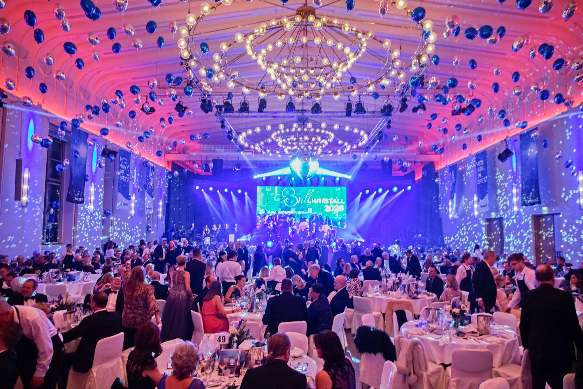 Gäste sitzen im geschmückten Gürzenich an runden Tischen.