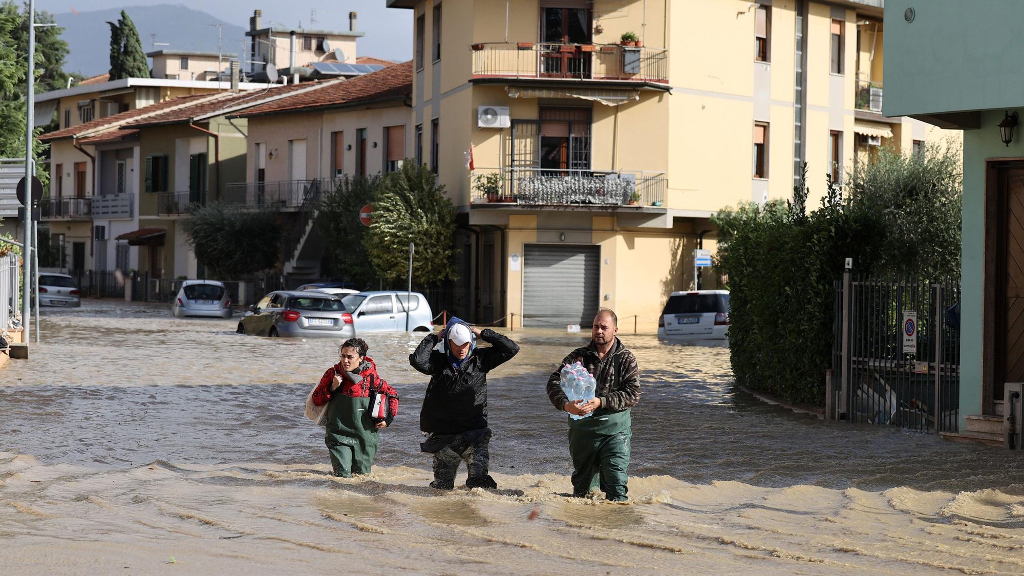 dpatopbilder - 03.11.2023, Italien, Toskana: Menschen gehen im Hochwasser über eine überschwemmte Straße. Schwere Unwetter mit heftigen Regenfällen haben die mittelitalienische Region Toskana in der Nacht zum Freitag heimgesucht. Foto: Str/Xinhua/dpa +++ dpa-Bildfunk +++