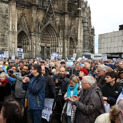 Menschen stehen mit Israel-Flaggen vor dem Kölner Dom.