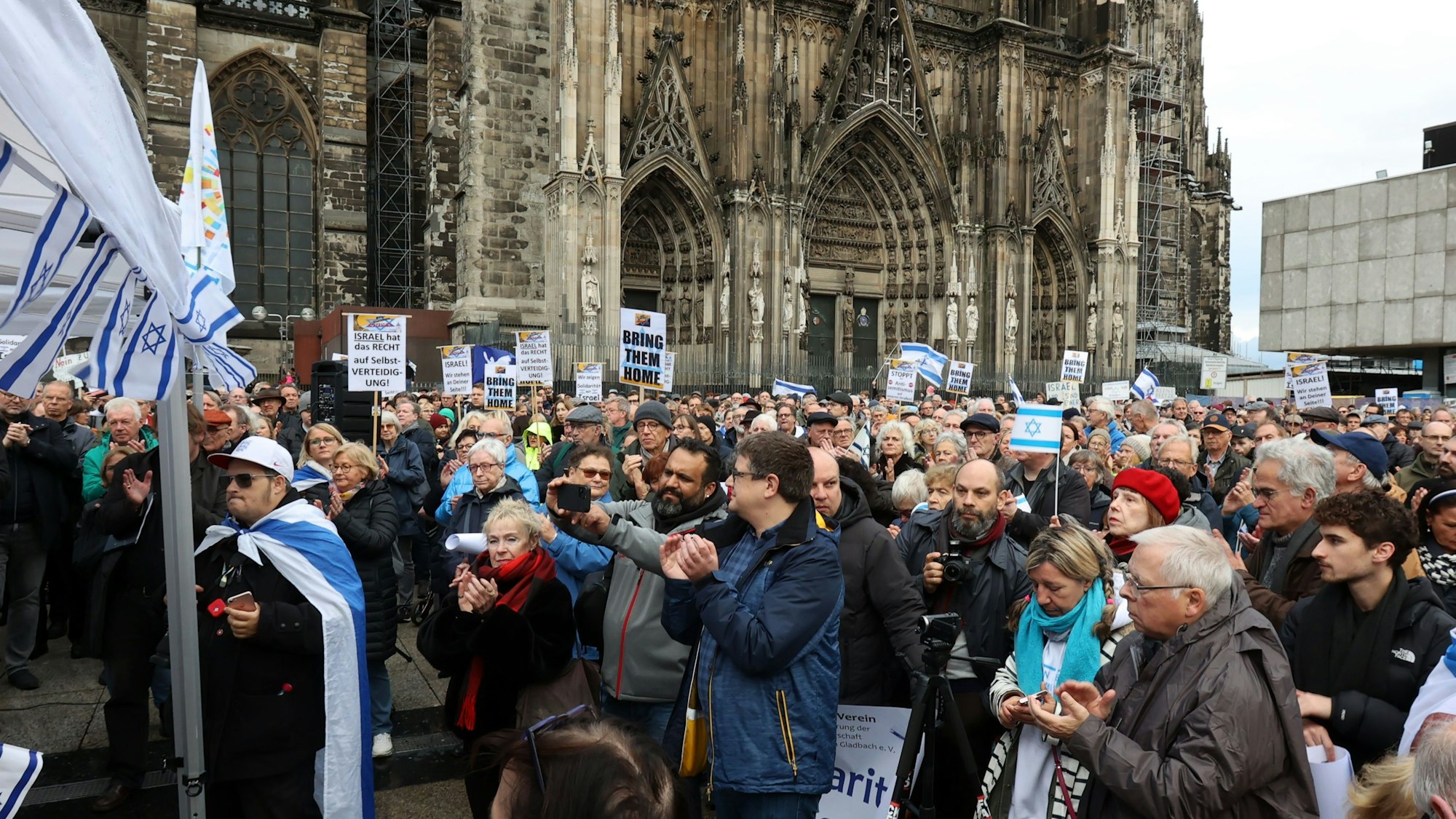 Menschen stehen mit Israel-Flaggen vor dem Kölner Dom.