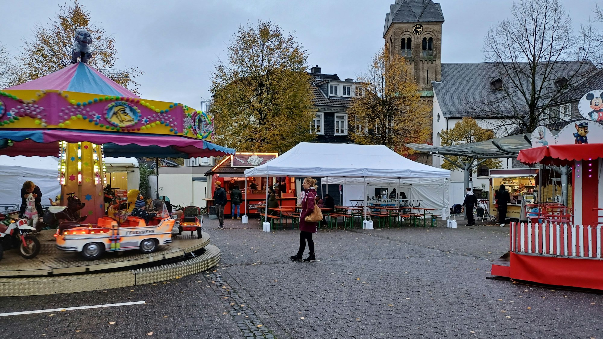 Eine Frau geht über einen leeren Markt mit Ständen in Burscheid.
