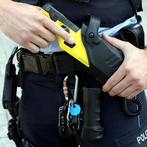 Ein Kölner Polizist zieht eine Elektroschock-Waffe aus dem Gürtel.