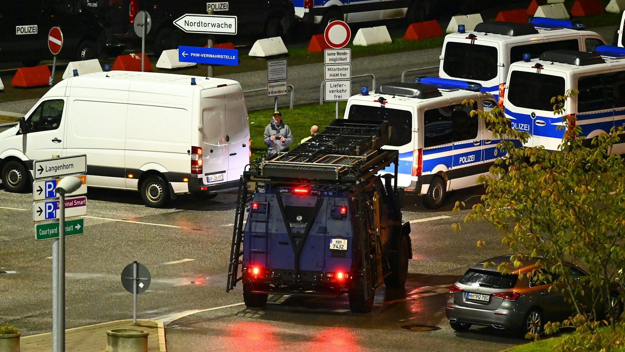 Polizeiautos und ein Spezialfahrzeug stehen am Flughafen. Der Hamburger Flughafen ist nach dem Eindringen eines Fahrzeugs auf das Gelände gesperrt worden.