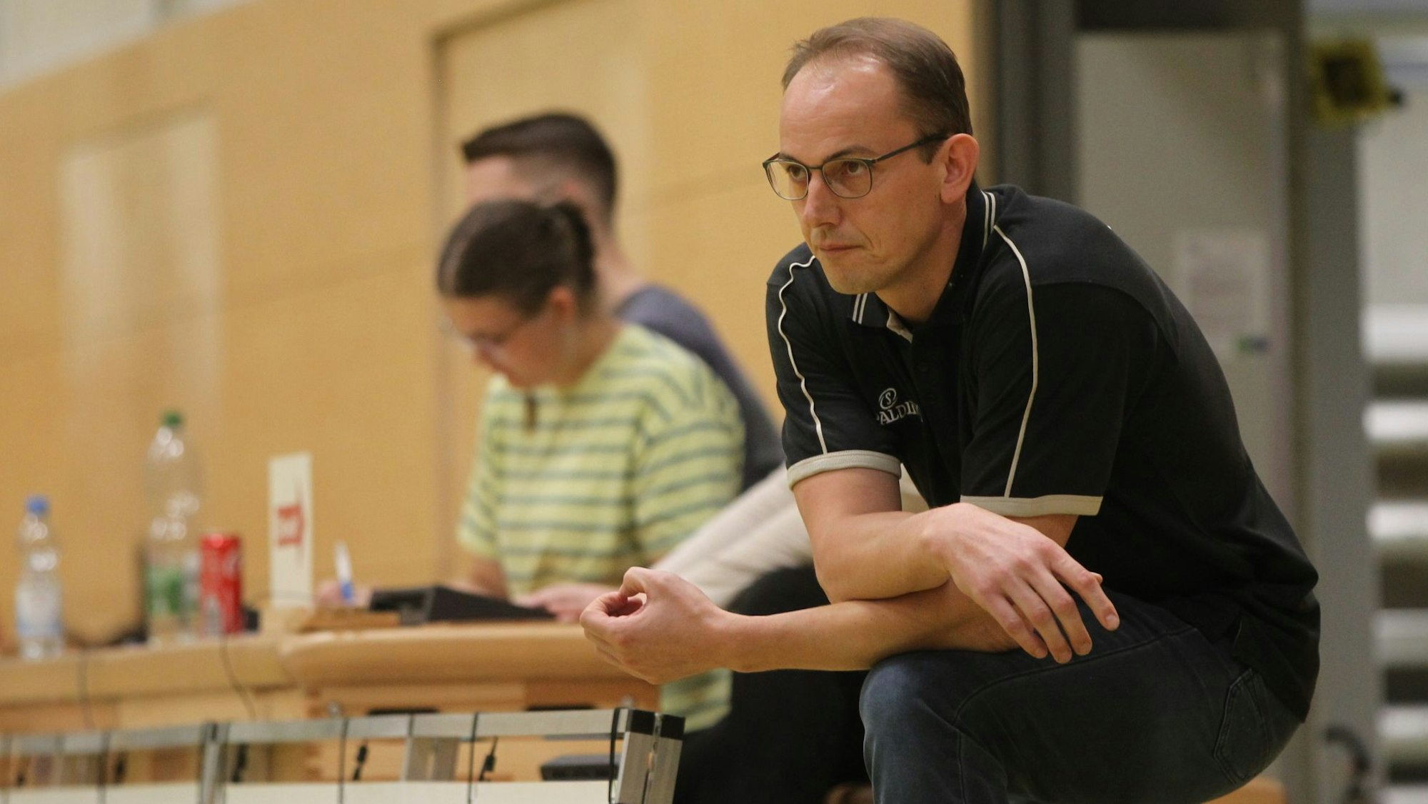 Trainer Florian Hammes schaut gebannt zu. Er lehnt mit den Armen auf einem Knie.