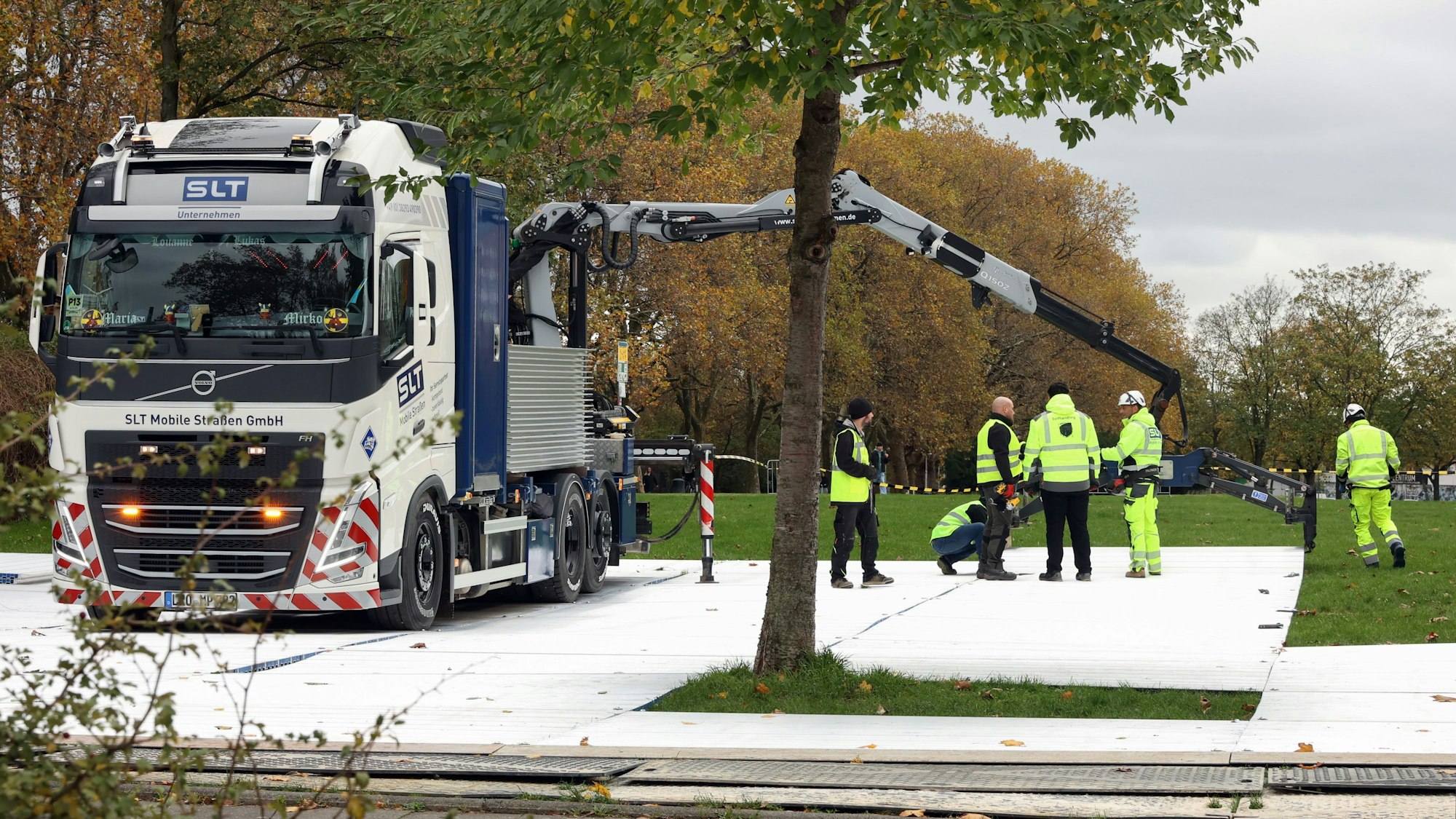 Ein Lkw-Kran platziert eine Platte auf der Uniwiese.
