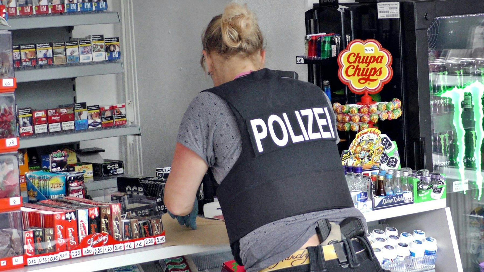 Eine Polizeibeamtin sichert in einem Kiosk Spuren