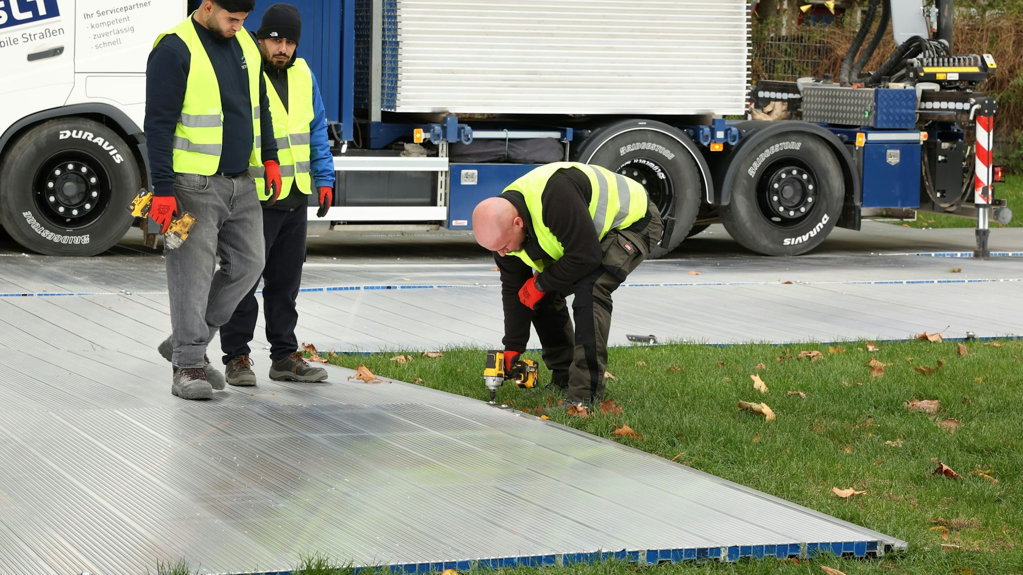 Arbeiter schrauben eine Platte fest.