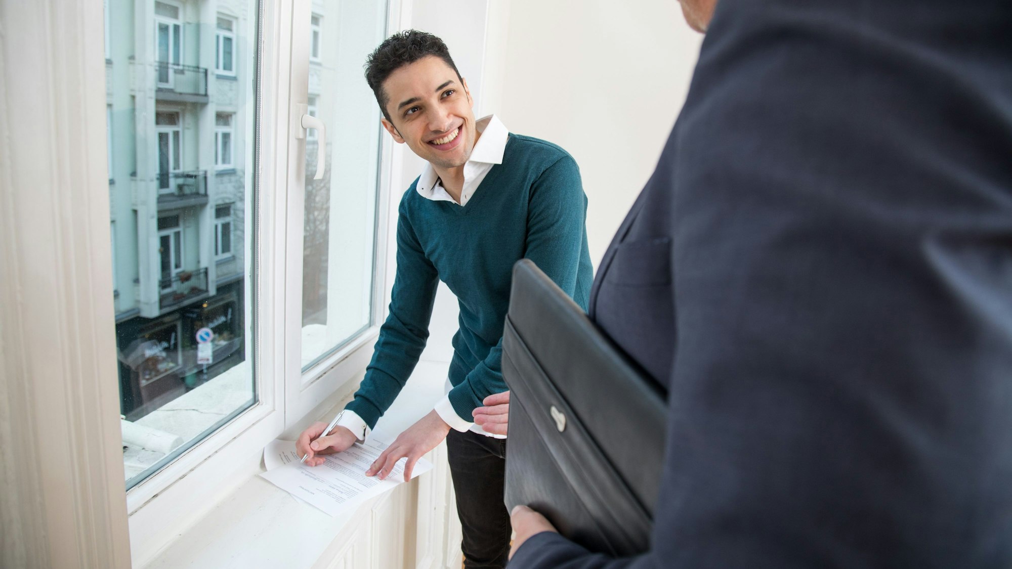 Junger Mann unterschreibt lächelnd einen Mietvertrag