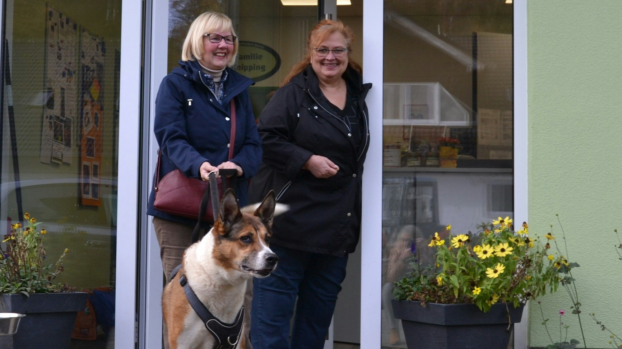 Zwei Frauen stehen in der Tür mit einem Hund.
