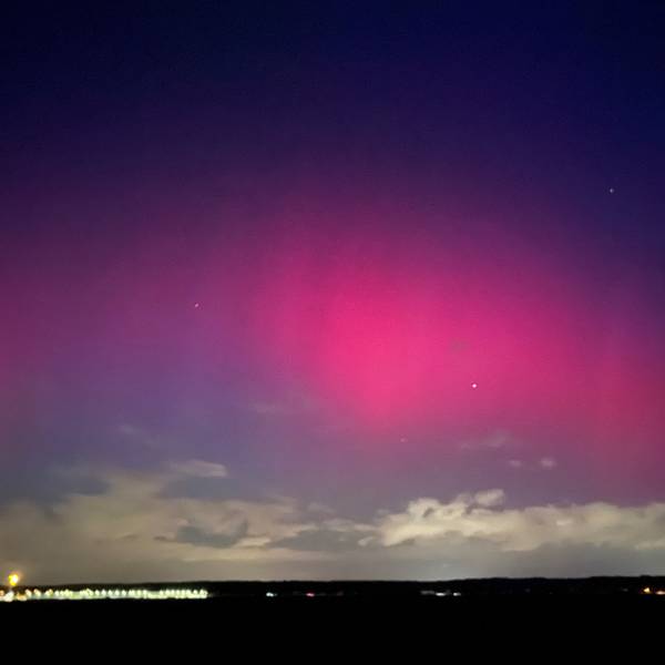 Das Bild zeigt ein pink-rötliches Nordlicht.