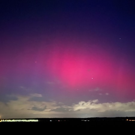 Das Bild zeigt ein pink-rötliches Nordlicht.