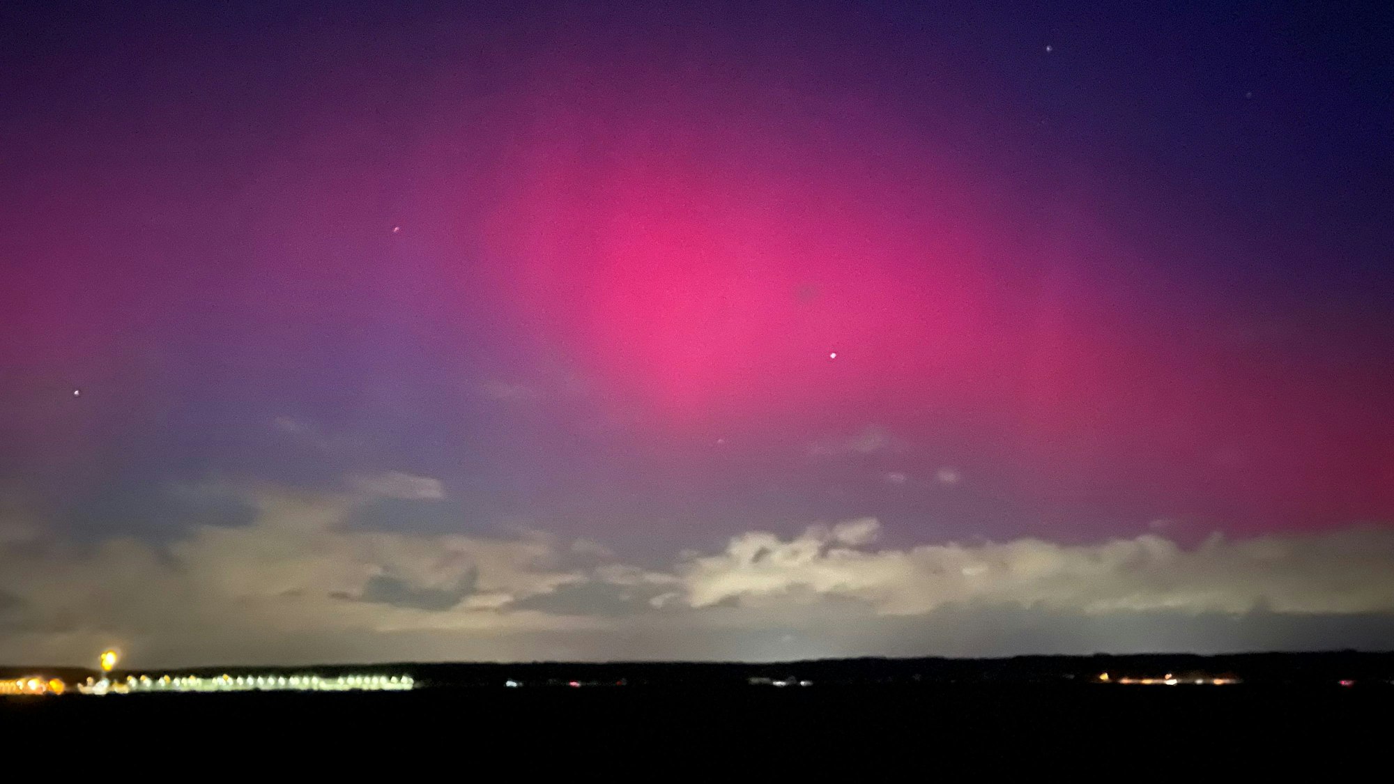 Das Bild zeigt ein pink-rötliches Nordlicht.