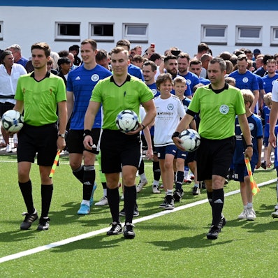 Beide Mannschaften betreten mit den Schiedsrichtern den Rasen.