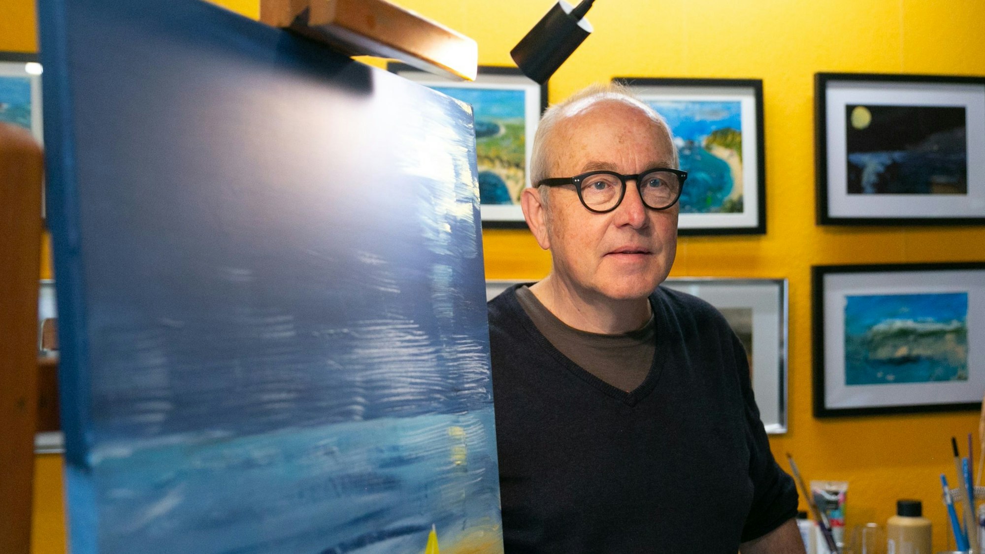 Der Künstler Achim Lahr steht neben einer Leinwand in seinem Atelier in Engelskirchen.