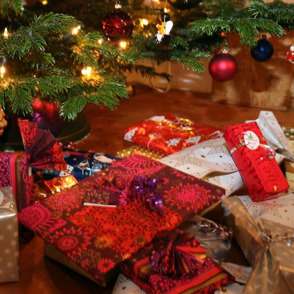 Verpackte Weihnachtsgeschenke liegen unter einem Christbaum.
