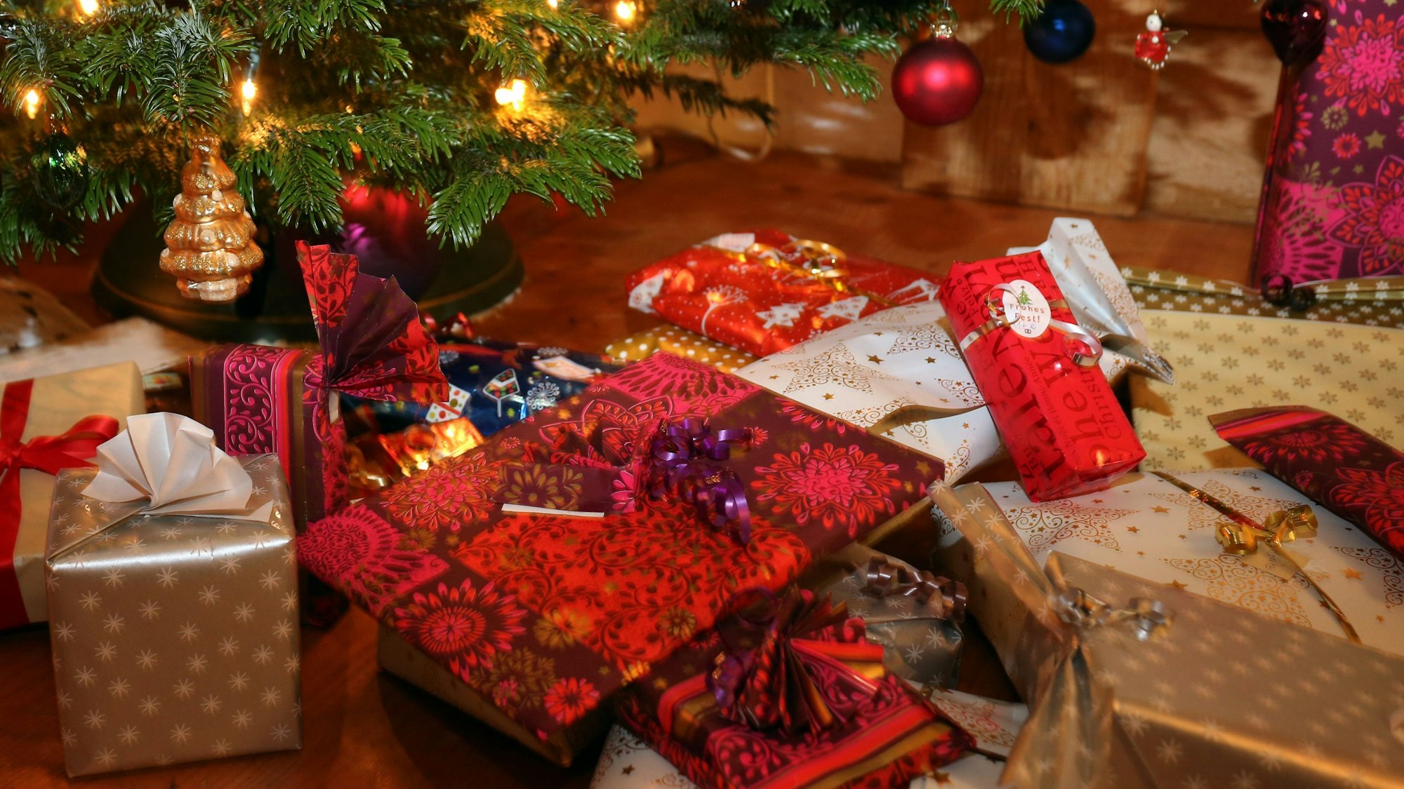 Verpackte Weihnachtsgeschenke liegen unter einem Christbaum.