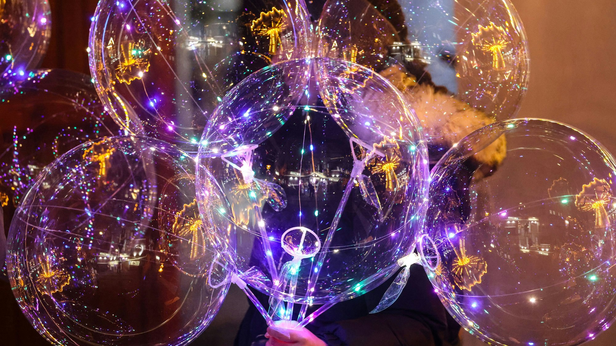 Eine Frau verkauft auf dem Weihnachtsmarkt leuchtende Ballons.