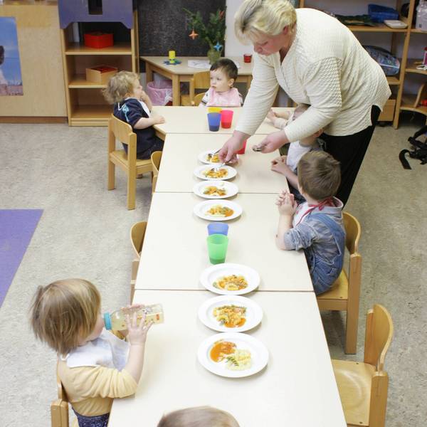 Kinder mit Erzieherin beim Mittagessen