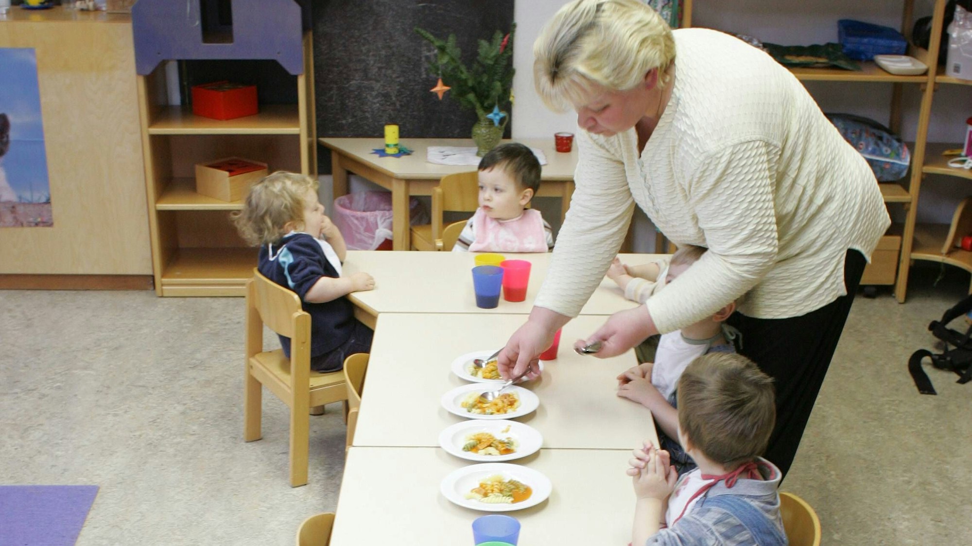 Kinder mit Erzieherin beim Mittagessen