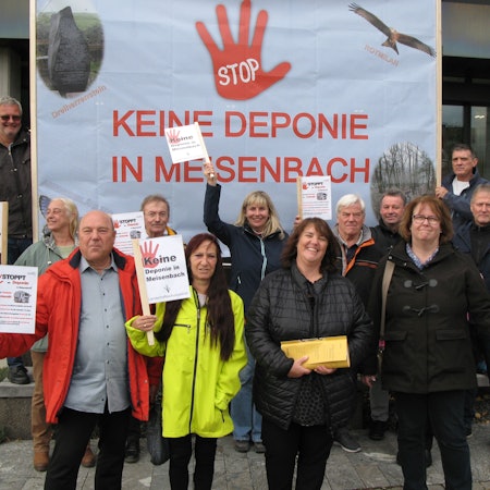 Zwölf Männer und Frauen halten Schilder und ein großes Transparent hoch, auf dem steht: Stop, keine Deponie in Meisenbach.