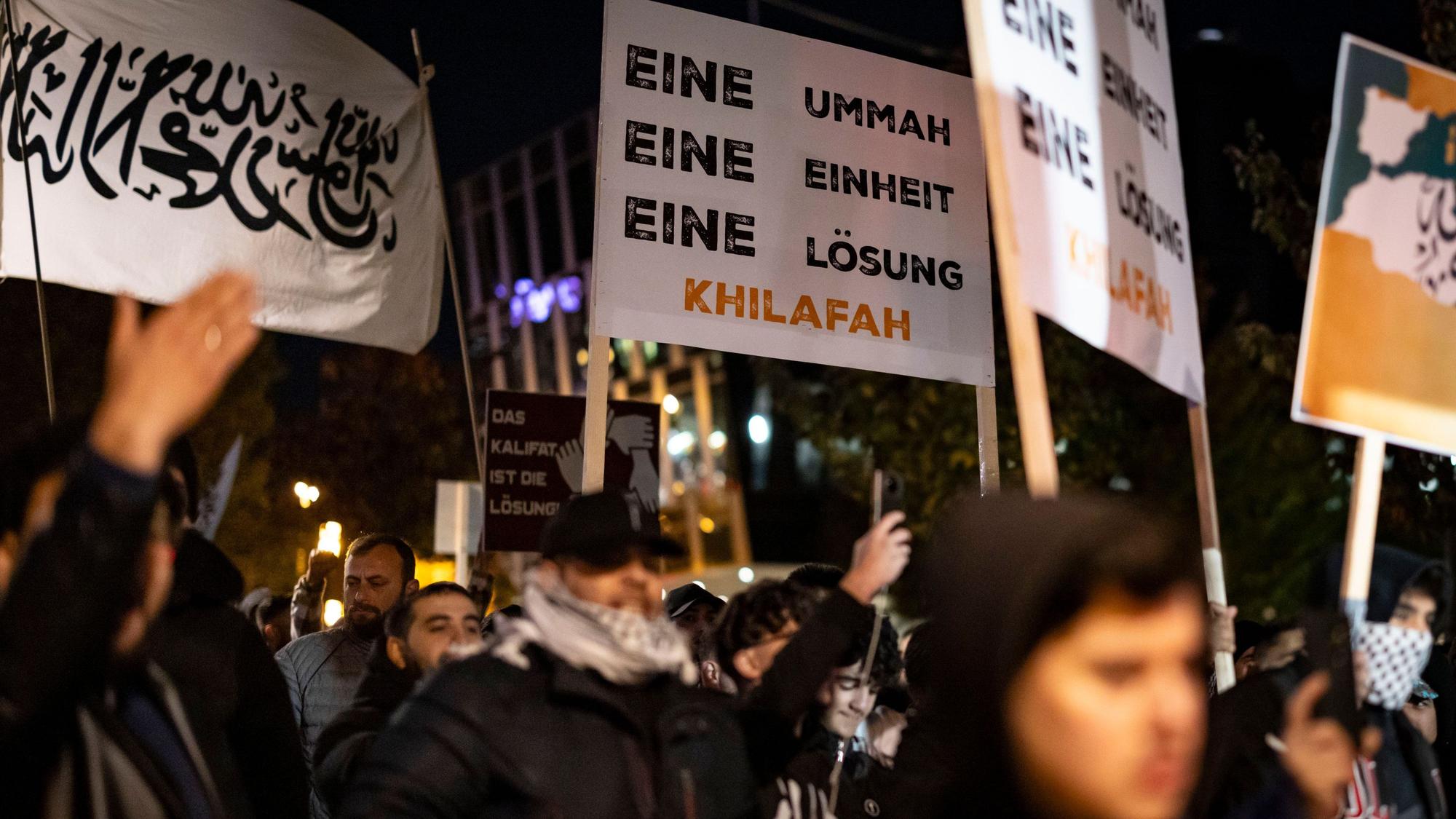 03.11.2023, Nordrhein-Westfalen, Essen: Schilder und Fotos werden gezeigt bei der Kundgebung "Gaza unter Beschuss - gemeinsam gegen das Unrecht". Begleitet von starken Kräften der Polizei Demo in Essen: Teilnehmer fordern auf Bannern ein islamistisches Kalifat.die Teilnehmer gegen den israelischen Militäreinsatz im Gazastreifen. Angemeldet worden war die pro-palästinensische Demonstration von einer Privatperson. Foto: Christoph Reichwein/dpa +++ dpa-Bildfunk +++
