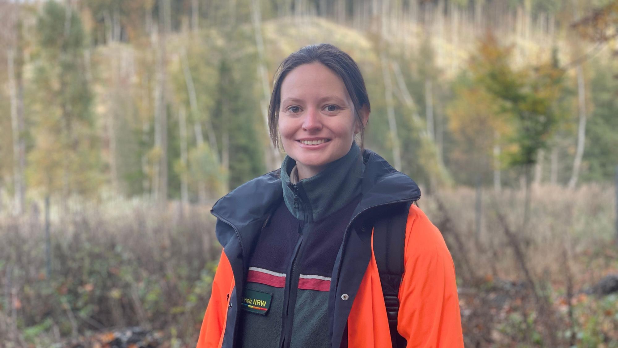 Catharina Schmidt vom Forschungsnetzwerk Wald steht auf einer kahlen Waldfläche, im Hintergrund sind Stämme und einige Bäume zu sehen.