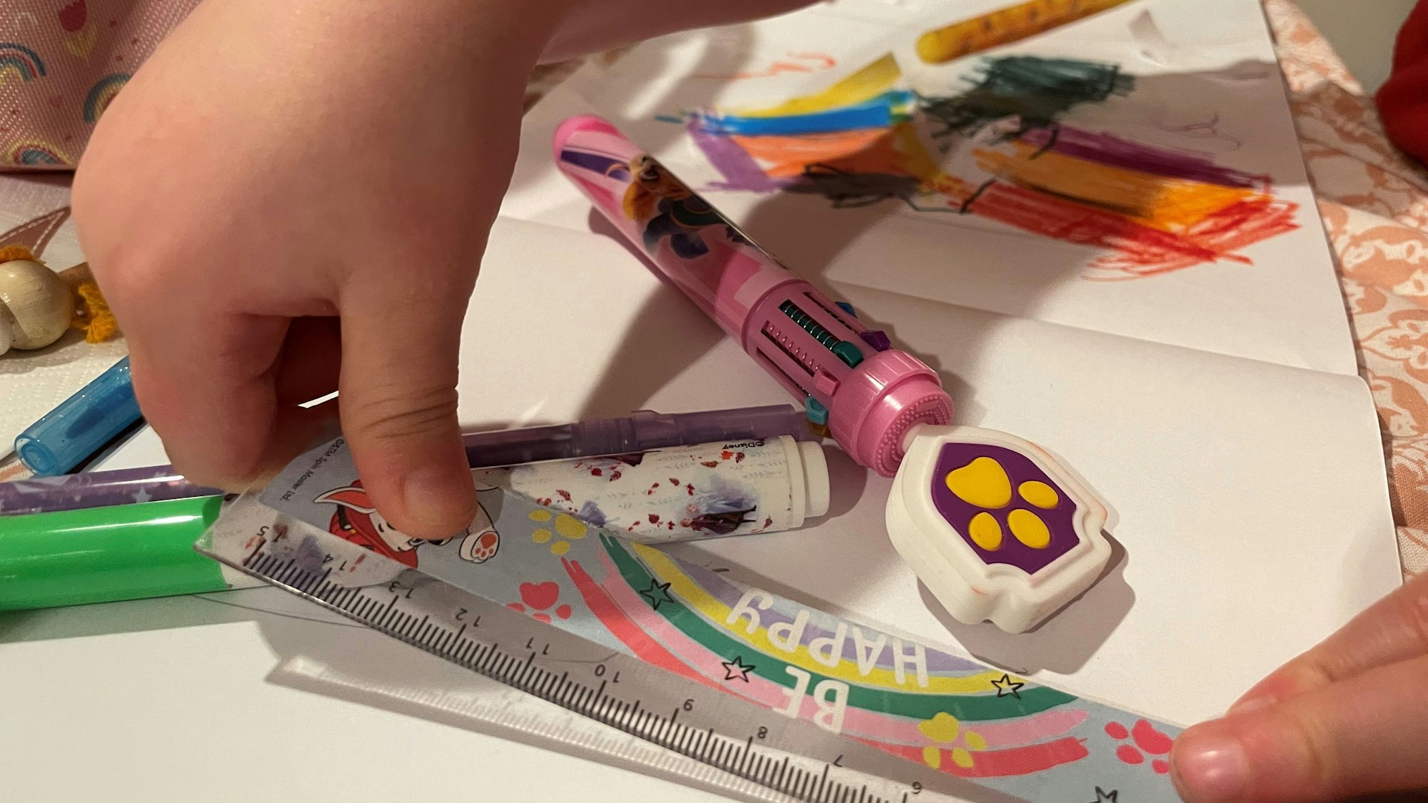 Das Bild zeigt ein Kind, das mit einem Lineal und Stiften beschäftigt ist.