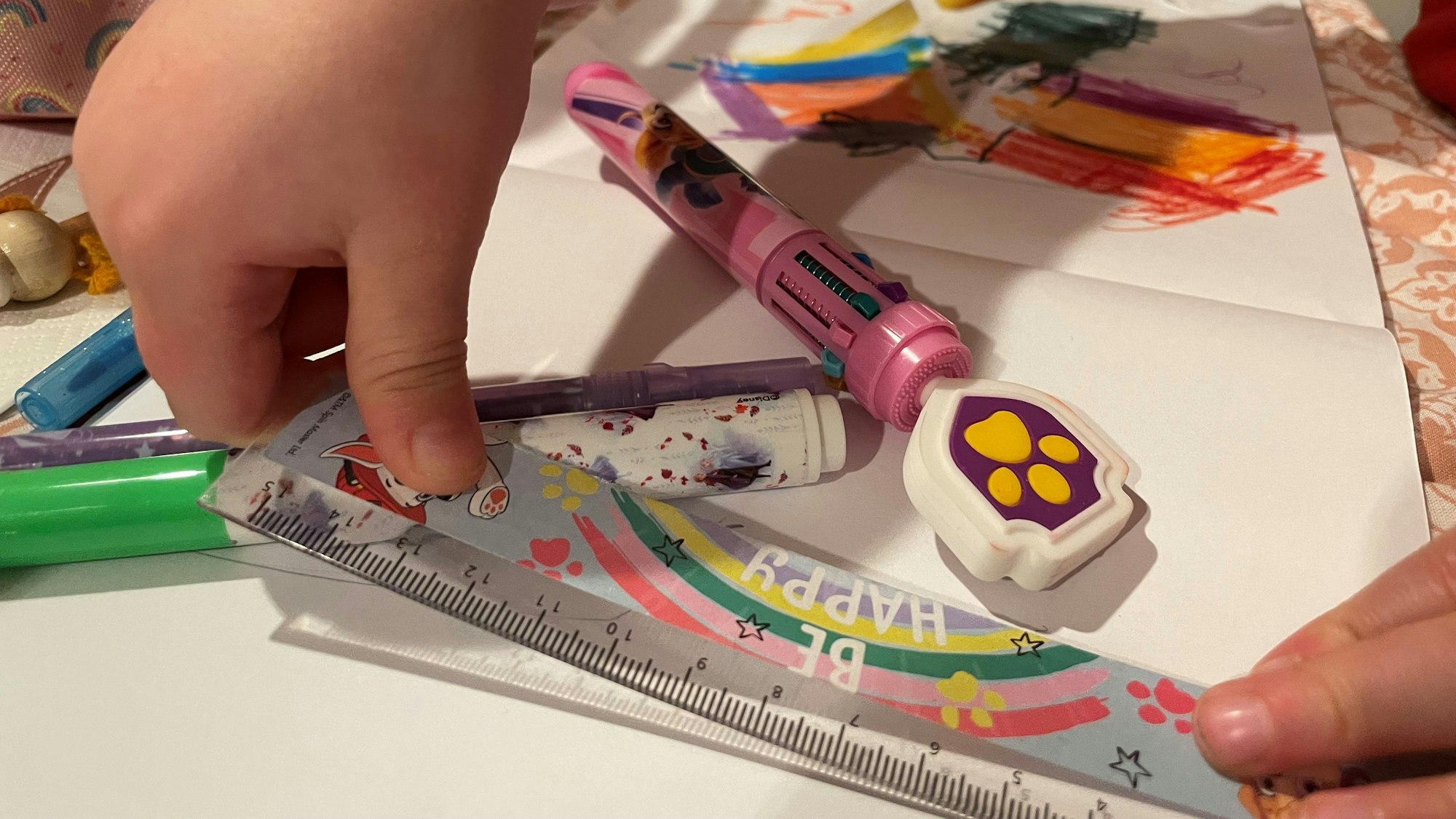 Das Bild zeigt die Hände eines Kita-Kindes, das ein Lineal in den Händen hält. Auch Stifte und Papier sind zu sehen.