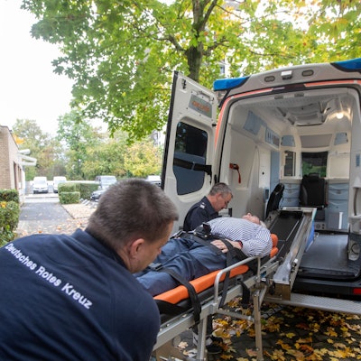 Walter (vorne) und Wolfgang Blierbach transportieren Karsten Möring auf der Bahre in den neuen Krankenwagen des DRK Porz.