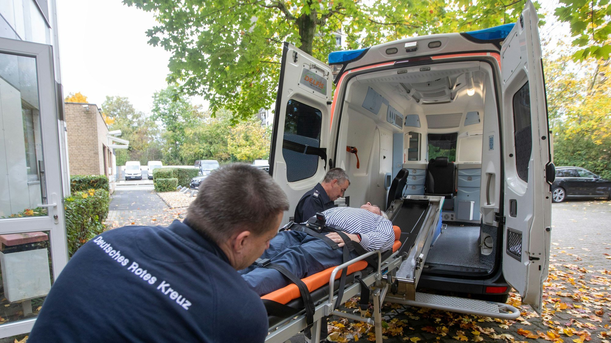 Walter (vorne) und Wolfgang Blierbach transportieren Karsten Möring auf der Bahre in den neuen Krankenwagen des DRK Porz.