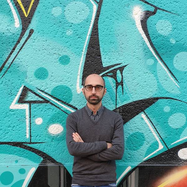 Islamexperte Eren Güvercin mit verschränkten Armen vor einem Graffiti