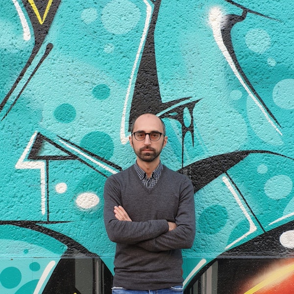 Islamexperte Eren Güvercin mit verschränkten Armen vor einem Graffiti