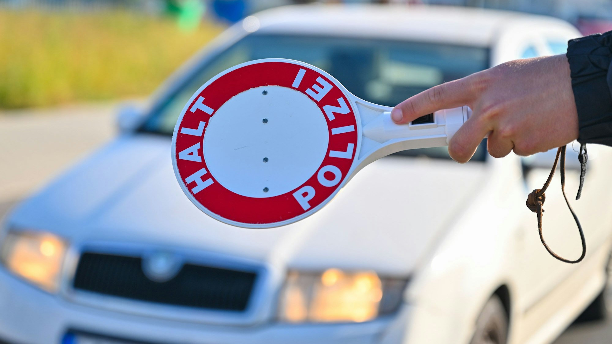 Ein Polizeibeamter stoppt einen Autofahrer mit einer Anhaltekelle.
