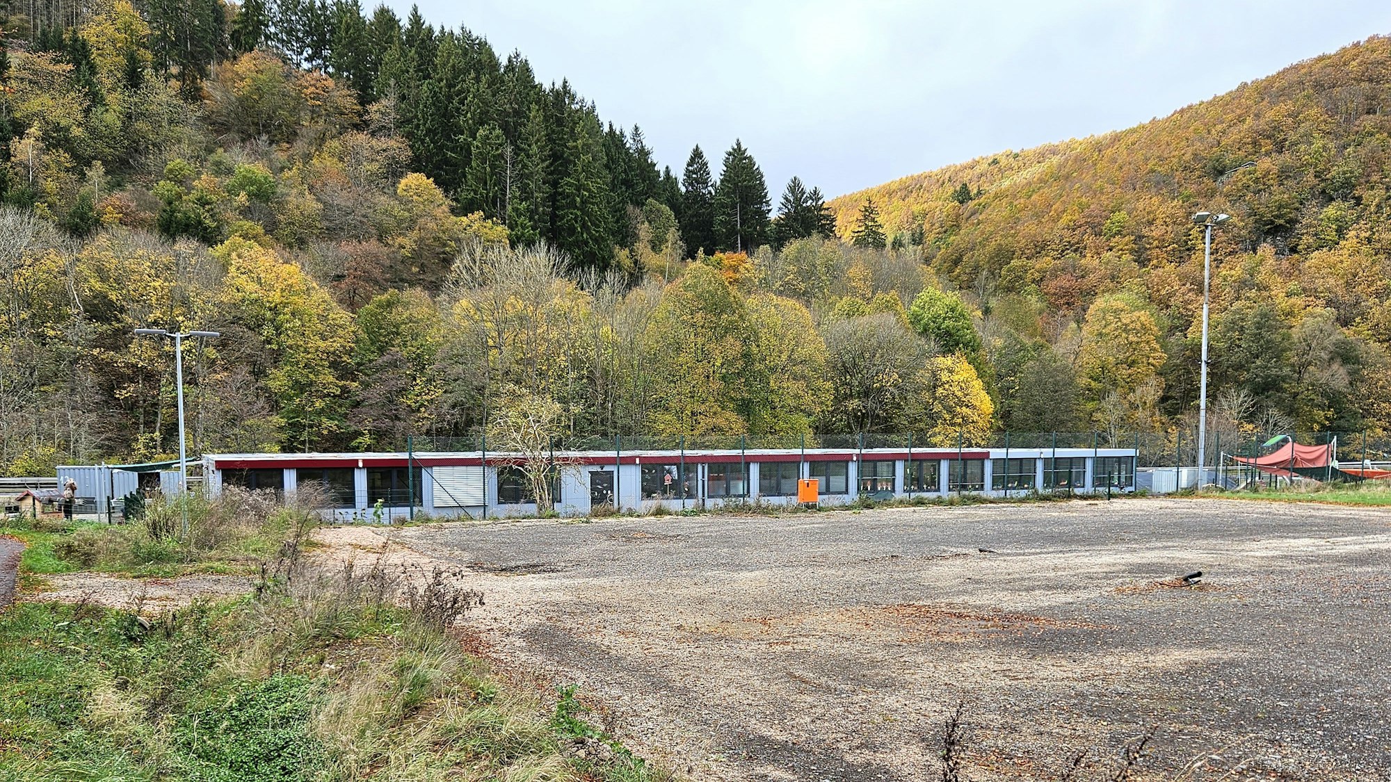 Zu sehen ist ein eingeebneter Platz im Vordergrund und Wohncontainer im Hintergrund.