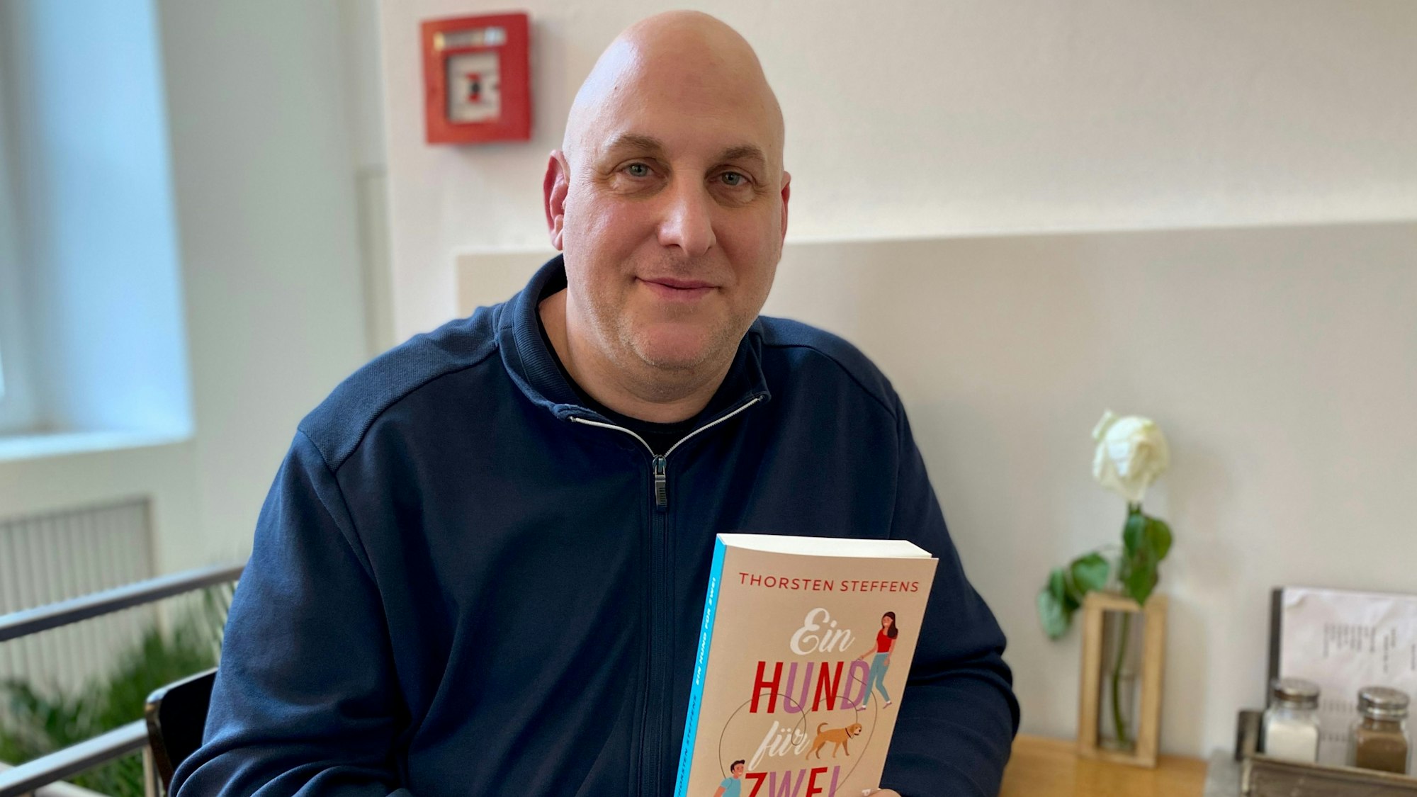 Zu sehen ist Autor Thorsten Steffens, der sein neues Buch in den Händen hält.