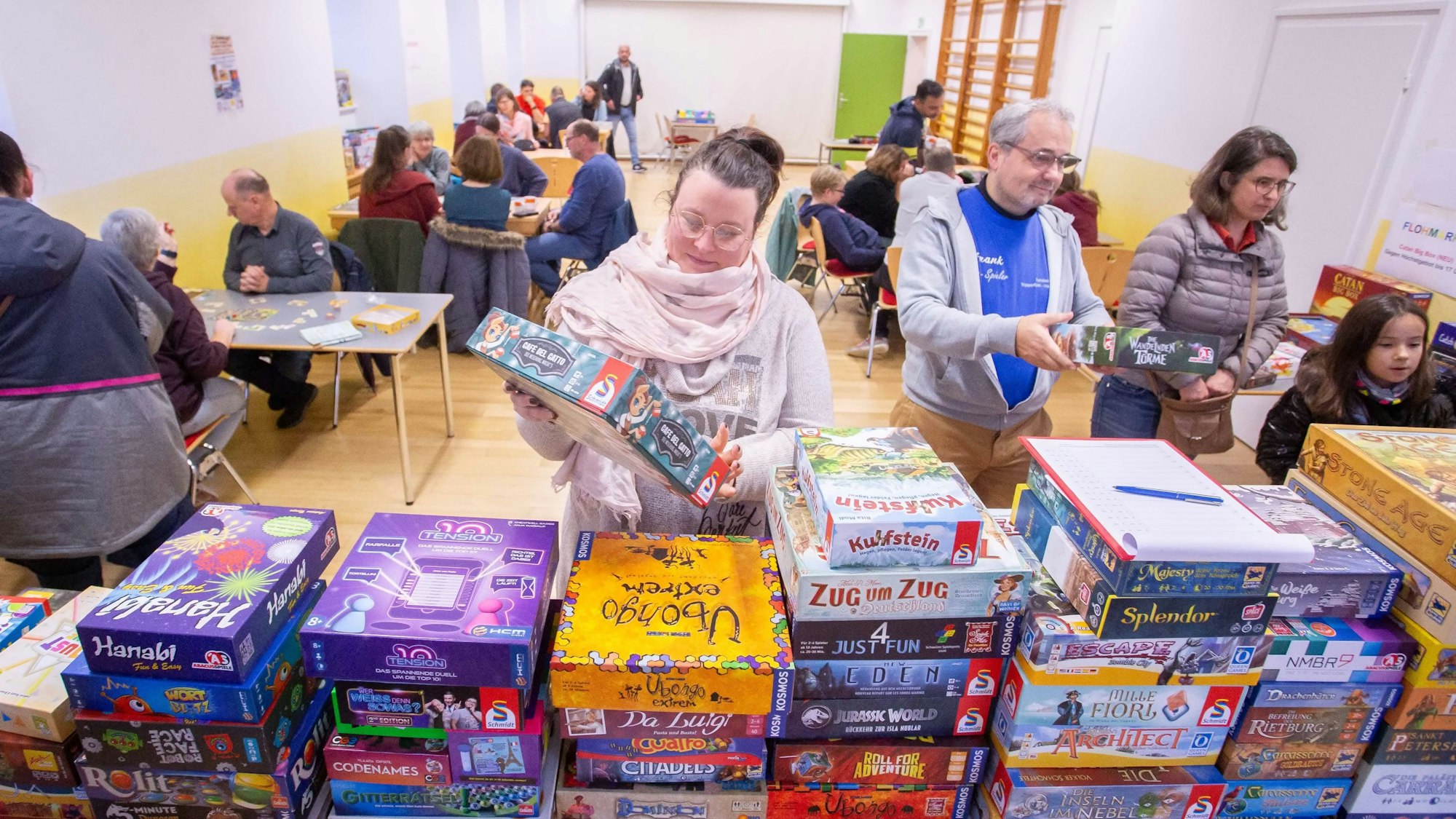 Das Foto zeigt Stabel mit Gesellschaftsspielen und Spieler im Hintergrund