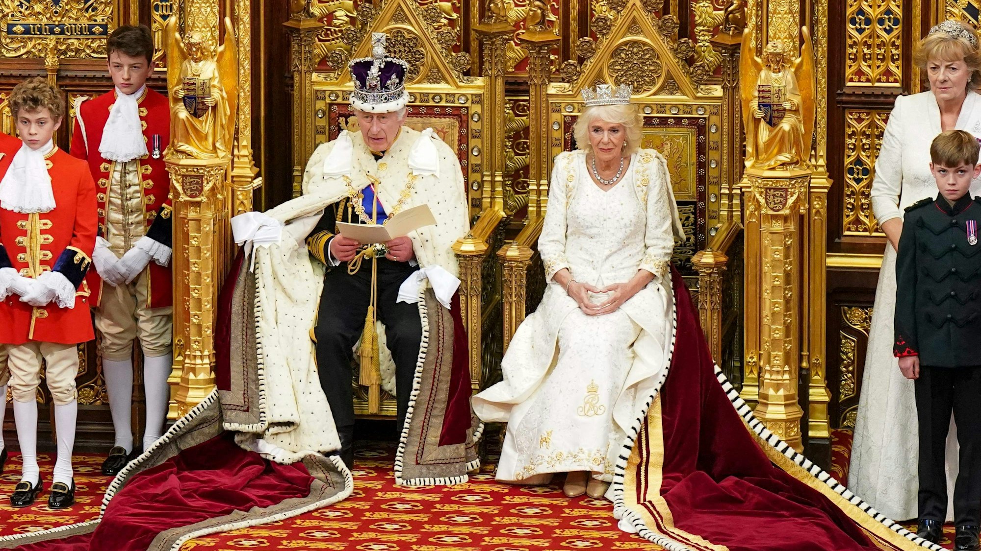 Königin Camilla, die das Staatsdiadem von George IV. trägt, sitzt neben dem britischen König Charles III., der die kaiserliche Staatskrone und den Staatsmantel trägt, während er vom Thron des House of Lords aus die Rede des Königs während der Eröffnung des Parlaments in den Houses of Parliament verliest.