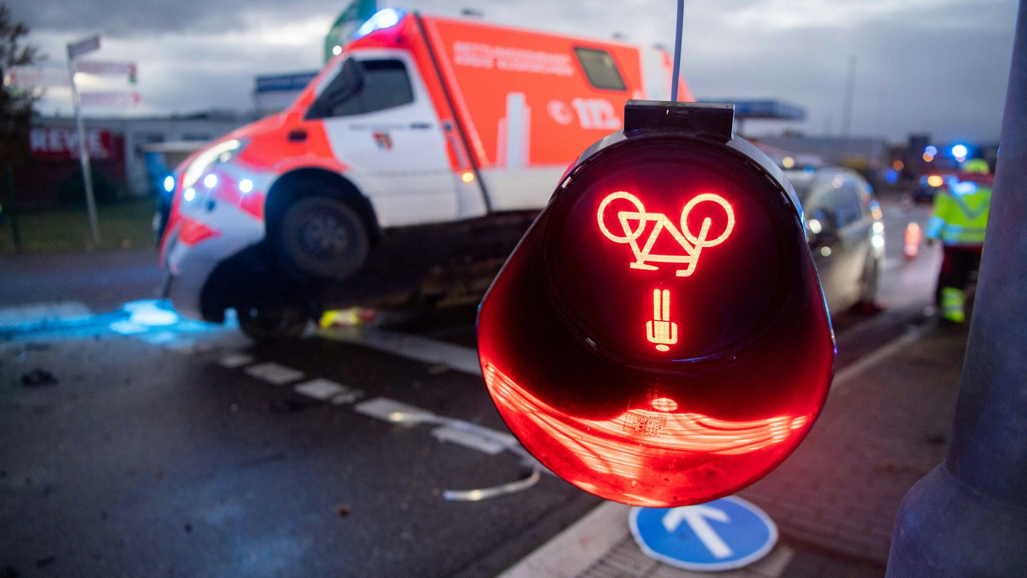 Das Bild zeigt einen Unfall in Kommern. Im Hintergrund ist ein Rettungswagen verunglückt, im Vordergrund hängt eine zerstörte Fußgängerampel herab.