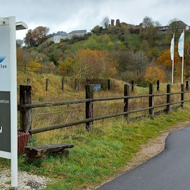 Ein Schild an der Einfahrt zum Ferienpark in Kronenburg, im Hintergrund ist das Dorf zu sehen.