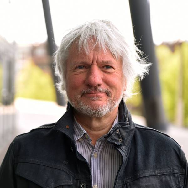 Kabarettist Jürgen Becker steht vor der Lanxess-Arena. Er trägt eine dunkle Jacke und blickt in die Kamera.